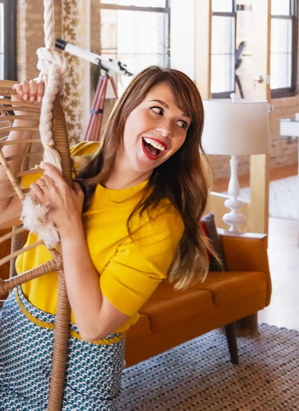 Founder of DesignScout, Scout Driscoll, swinging from a hanging egg chair in their studio.